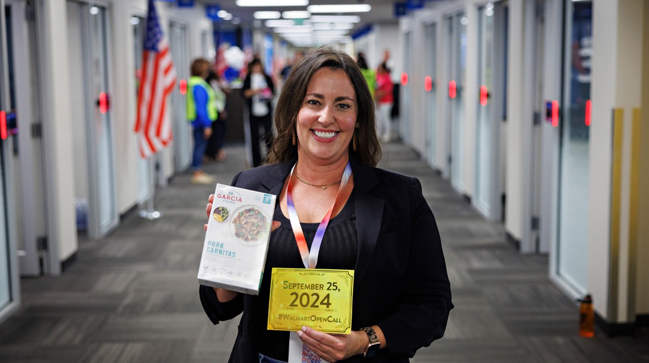 Supplier smiling at the camera while holding up signs from Walmart Open Call 2024